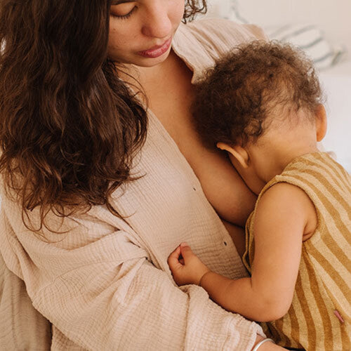 Una madre amamanta a su hijo mientras está sentada en la cama - Mustela España - 1