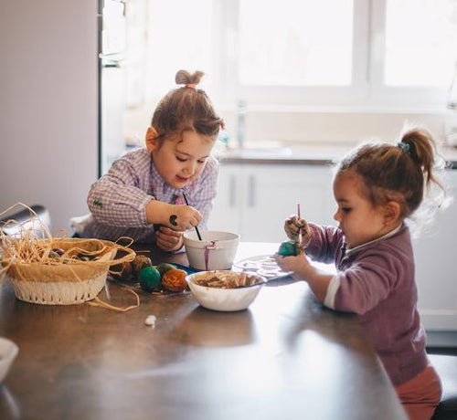 Dos hermanas pintan huevos de pascua en la cocina de su casa - Mustela España - 1