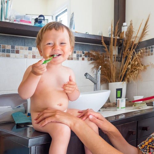 Un bebé feliz se cepilla los dientes por primera vez, sentado en el baño de su hogar y en compañía de su mamá - Mustela España - 1