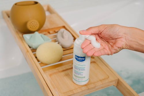 Mujer en el baño de su casa aplicándose espuma de shampoo Mustela en la mano - Mustela España - 2