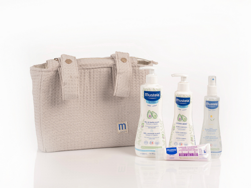 Nueva bolsa para carricoche de Mustela con dos asitas y cremallera de color beige. A su derecha los 4 productos que se incluyen: gel de baño, crema pañal, leche hidratante y agua para peinar. - Mustela España - 4