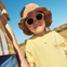 Bebé entre 1 y 2 años disfruta de un día soleado en el parque con las gafas de sol aguacate de Mustela by Parafina en color amarillo.
