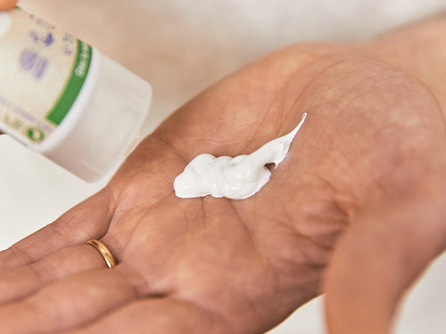 Padre aplica en la palma de la mano un poco de crema para la dermatitis del pañal, o también llamada pañalitis. - Mustela España - 3