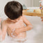 Un niño está tomando su baño con el aceite de ducha Stelatopia Mustela, que hace espuma