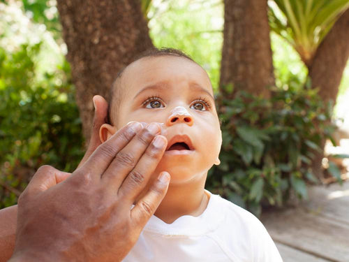 Un padre pone crema solar en la cara de su niño. slider - Mustela España - 3