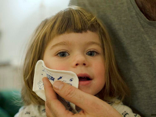 Un padre está limpiado la cara de su niña con una ecotoallita discos de algodón BIO - Mustela España - 5