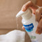 Madre aplica el agua limpiadora de Mustela en una toallita reutilizable de bebé con el dosificador fácil