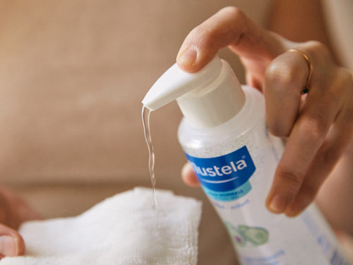 Una mamá aplica agua limpiadora micelar Mustela para bebés con su dosificador en una toallita - Mustela España - 4