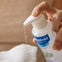 Una mamá aplica agua limpiadora micelar Mustela para bebés con su dosificador en una toallita 