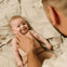 Un padre está aplicando la crema Stelatopia+ antipicor de Mustela en la cara de su bebé con piel atópica