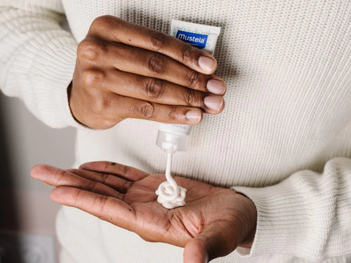 Padre se aplica un poco de crema facial para piel seca de Mustela en las manos para hidratar y nutrir la cara de su bebé. - Mustela España - 3