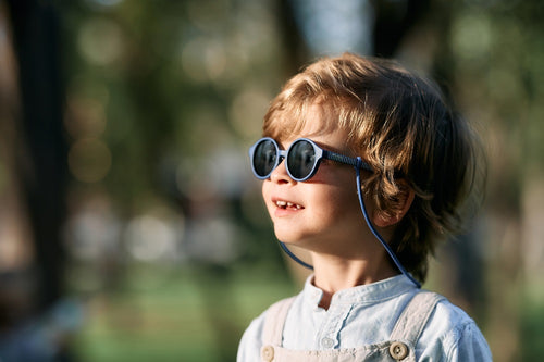 Bebé entre 1 y 2 años disfruta de un día soleado en el parque con las gafas de sol aguacate de Mustela by Parafina en color azul. slider - Mustela España - 2