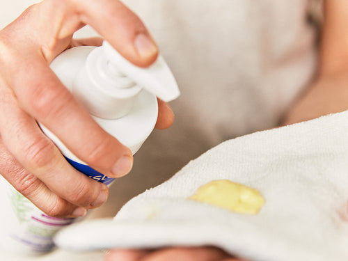 Madre aplica un poco de linimento Mustela en una toalla para limpiar con suavidad el culito de su bebé al cambiarle el pañal. - Mustela España - 3