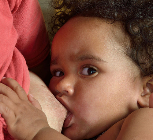 Bebé alimentándose del pecho de su madre donde se aprecian las típicas grietas del pezón. - Mustela España - 1