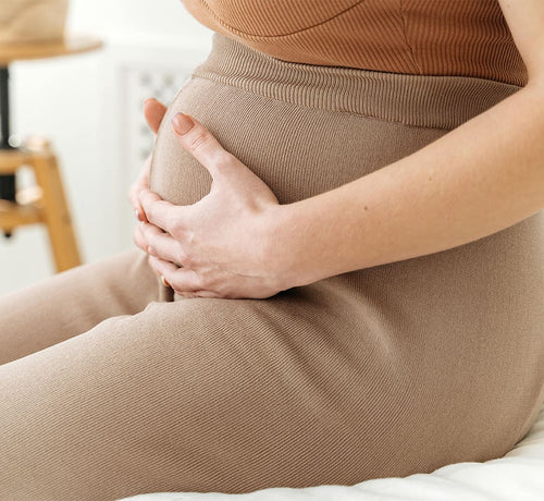 Mujer embarazada sentada abrazando su tripa - Mustela España - 1