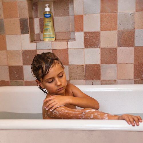 Niño en una bañera usando el aceite de ducha de Mustela. - Mustela España - 1