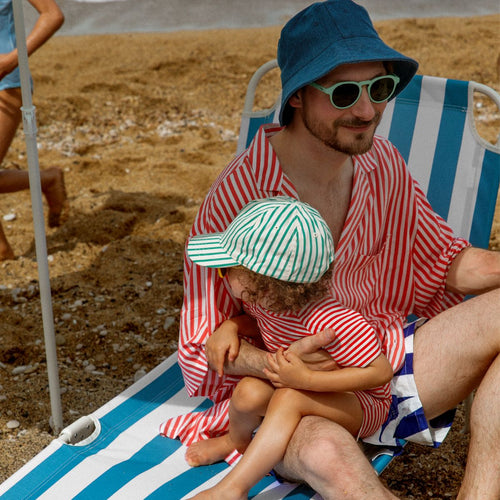 Un padre con su bebe en una silla de playa disfrutando em la playa - Mustela España - 1