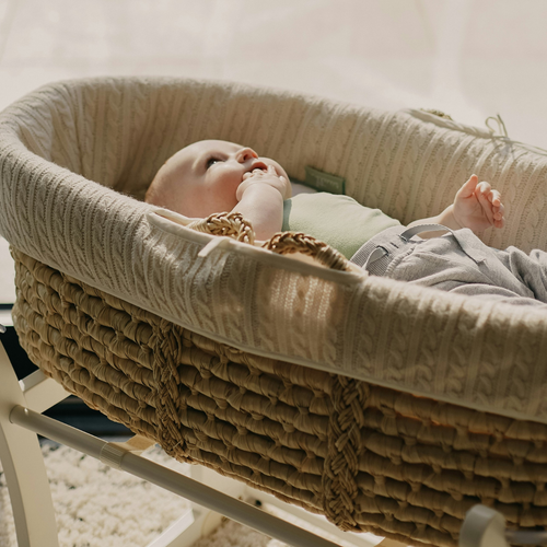 un bebé acostado sobre una cuna metiendo su mano en la boca - Mustela España - 1