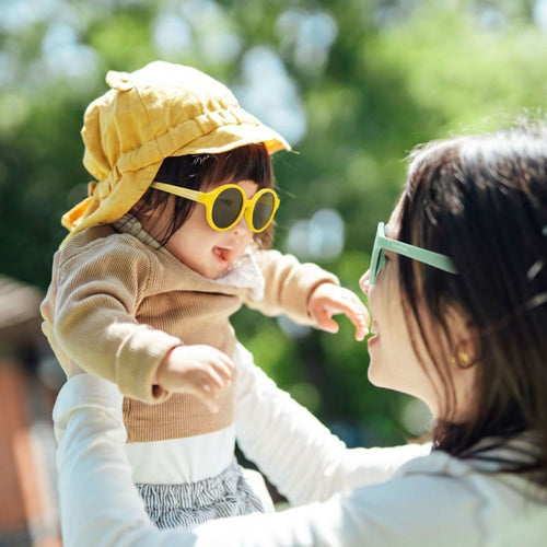 Madre levantando en eñll arire a su hija mientras llevan las dos unas buenas gafas de sol con las que proteger sus ojos - Mustela España - 1
