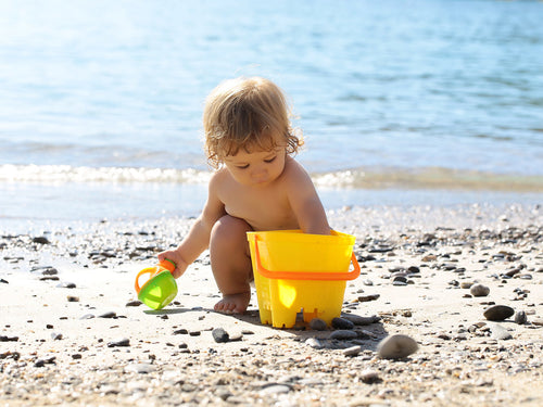 Un niño juega en la playa protegido por la crema solar Mustela adecuada, porque su madre conoce el fototipo de la piel de su bebé - Mustela España - 1