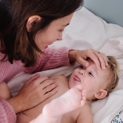 Mamá acariciando la cara de si hijo y este sacando la lengua y sube las piernas como refejo. - Mustela España - 1