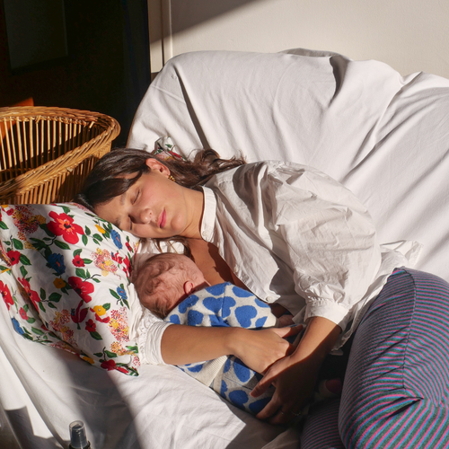 Una mamá dormida en un sillón mientras abraza a su bebé.. - Mustela España - 1