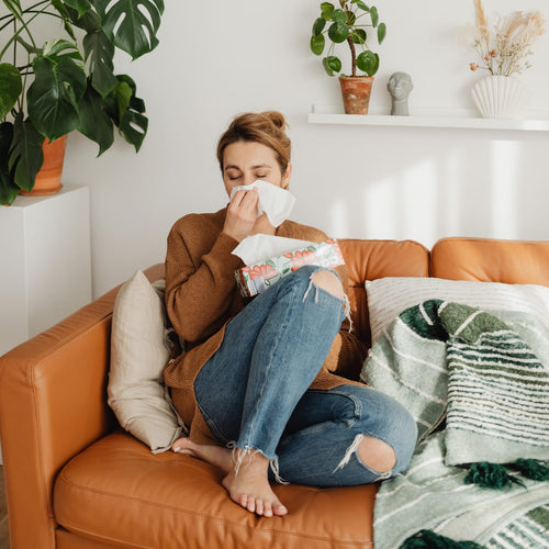mujer sonándose la nariz sentada en su sofa - Mustela España - 1