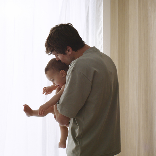 Papa dando un beso a su hijo en la nuca mientras o sostiene con sus brazos. - Mustela España - 1