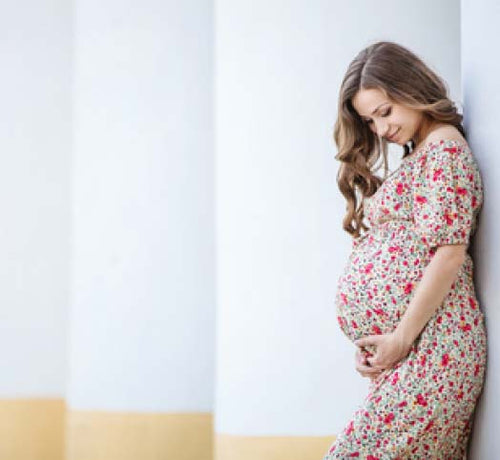 Mujer embarazada feliz se agarra la barriga tras usar productos Mustela para el cuidado de su piel e higiene intima. - Mustela España - 1