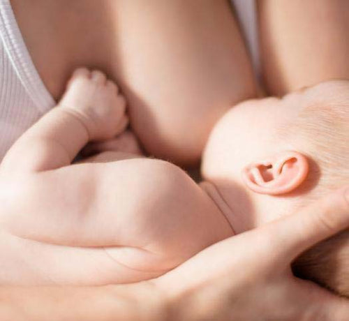 Una mamá da el pecho a su bebé mientras lo sujeta en brazos - Mustela España - 1