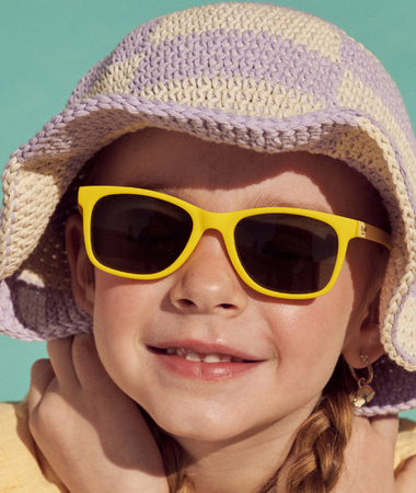 Una niña entre 3 y 5 años disfrutando del verano con los ojos protegidos del sol, lleva gafas de sol Girasol de color amarillo de Mustela by Parafina. 