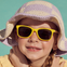 Una niña entre 3 y 5 años disfrutando del verano con los ojos protegidos del sol, lleva gafas de sol Girasol de color amarillo de Mustela by Parafina. slider