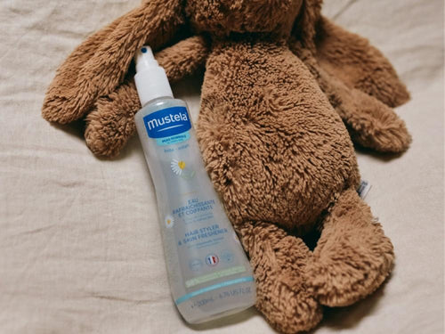 Bote de agua de peinado infantil de Mustela al lado de un peluche - Mustela España - 6