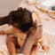 Un padre está peinando el cabello rizado de su niña después de aplicar el agua para peinar de Mustela