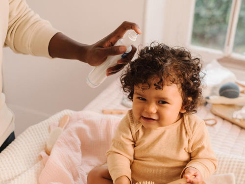 Una padre usa el Agua para peinar de Mustela en el pelo de su niña con pelo rizado. slider - Mustela España - 4