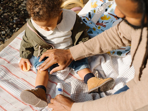 Padre aplica en la rodilla del bebé un poco de gel de árnica, crema para golpes y moratones de Mustela - Mustela España - 5