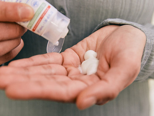 Padre se pone un poco de crema hidratante facial confort en la mano para aplicar en el rostro del bebé con piel sensible - Mustela España - 3