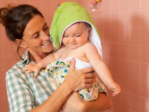 Una madre carga a su bebé envuelto en la capa de baño Mustela - Mustela España - 2