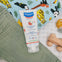 Bote de leche hidratante confort de Mustela junto con la ropa del bebé, pues es ideal para aplicar justo después del baño y aliviar las molestias de las piel sensible. 