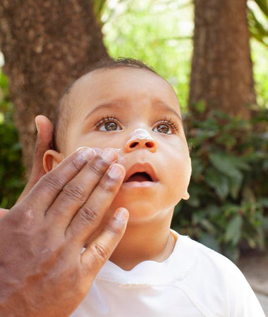 Un padre pone crema solar en la cara de su niño. 