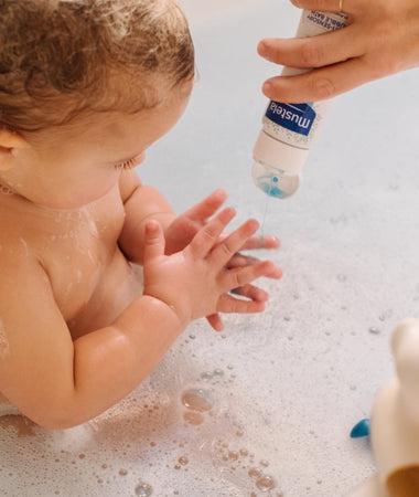 Bebé se da un baño de espuma agradable con el babygel con aguacate bio de Mustela, ideal para generar espuma ligera en la bañera apta para bebés. 