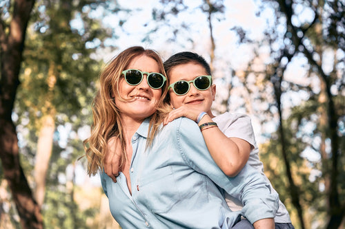 Una madre juega con su hijo en la montaña y llevan gafas de sol ecológicas de Mustela en color verde para proteger sus ojos. - Mustela España - 9