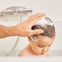 Un padre utiliza el gel de baño y ducha Stelatopia para limpiar el cabello de su niño.