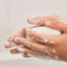 Una madre limpia con el jabón hidratante para manos, cara y cuerpo la piel seca de su bebé.
