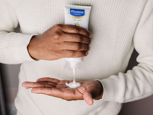 Padre aplica un poco de leche hidratante corporal para piel seca de Mustela en la palma de su mano. - Mustela España - 3