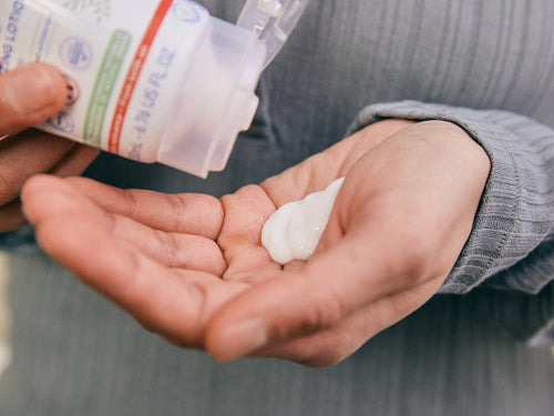 Padre se pone un poco de leche corporal hidratante confort en la mano para aplicar en la piel sensible de su bebé - Mustela España - 3