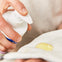 Madre aplica un poco de linimento Mustela en una toalla para limpiar con suavidad el culito de su bebé al cambiarle el pañal.