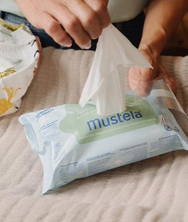 Una madre está sacando una toallita húmeda de su paquete. Son fáciles de sacar y conservar. 